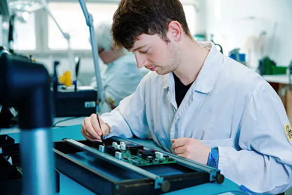 Mitarbeiter montiert Bauteile auf einer elektronischen Baugruppe