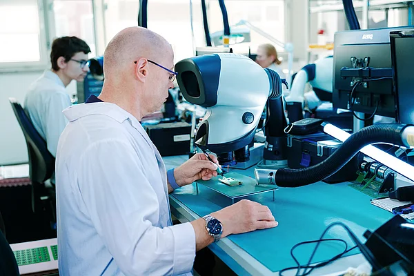 Mitarbeiter prüft eine Leiterplatte an einem optischen Prüfgerät