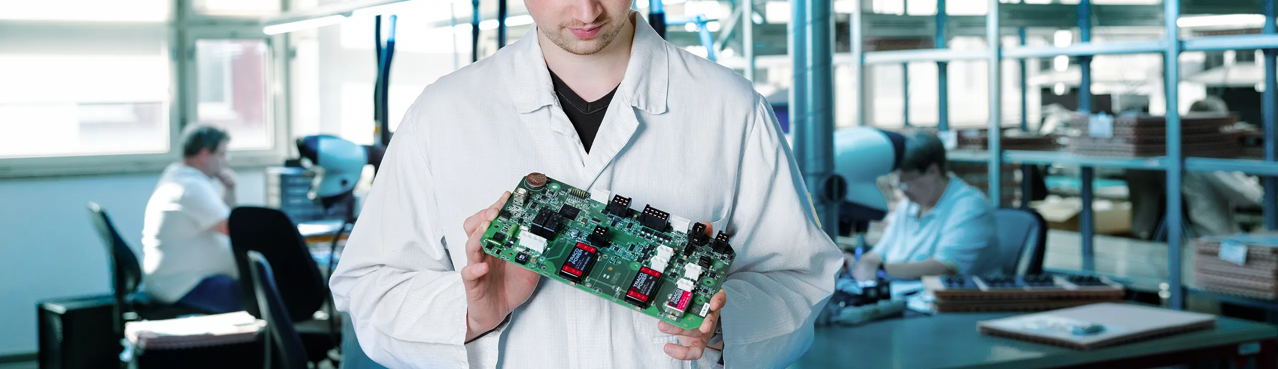 Mitarbeiter hält eine bestückte Leiterplatte in der Elektronikfertigung