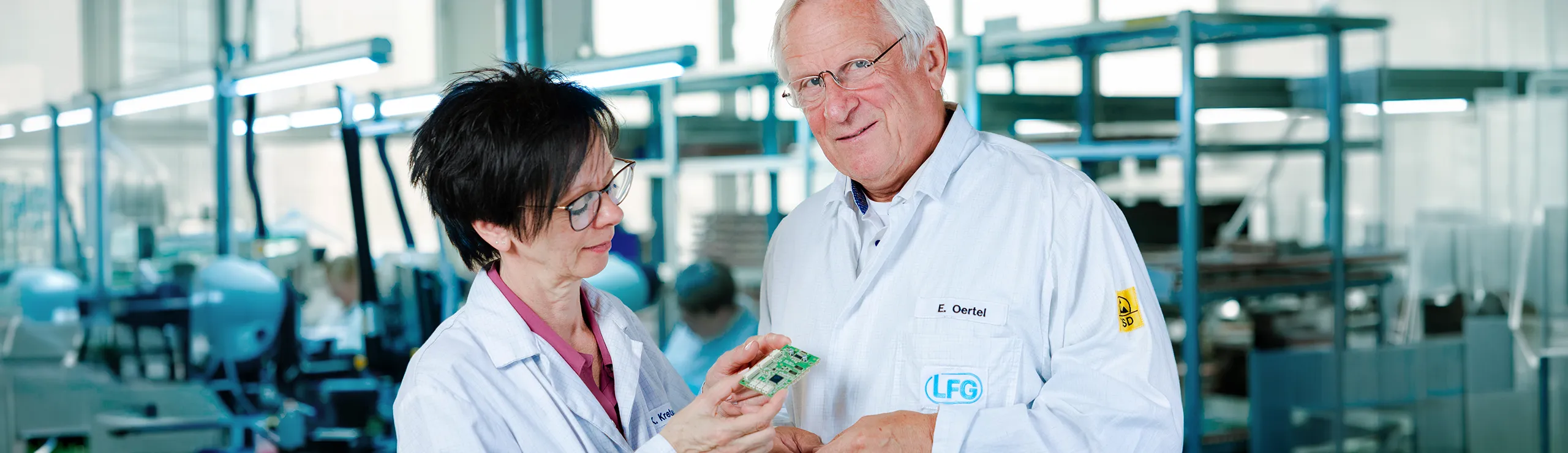 Zwei Mitarbeitende besprechen eine elektronische Baugruppe in der Fertigung